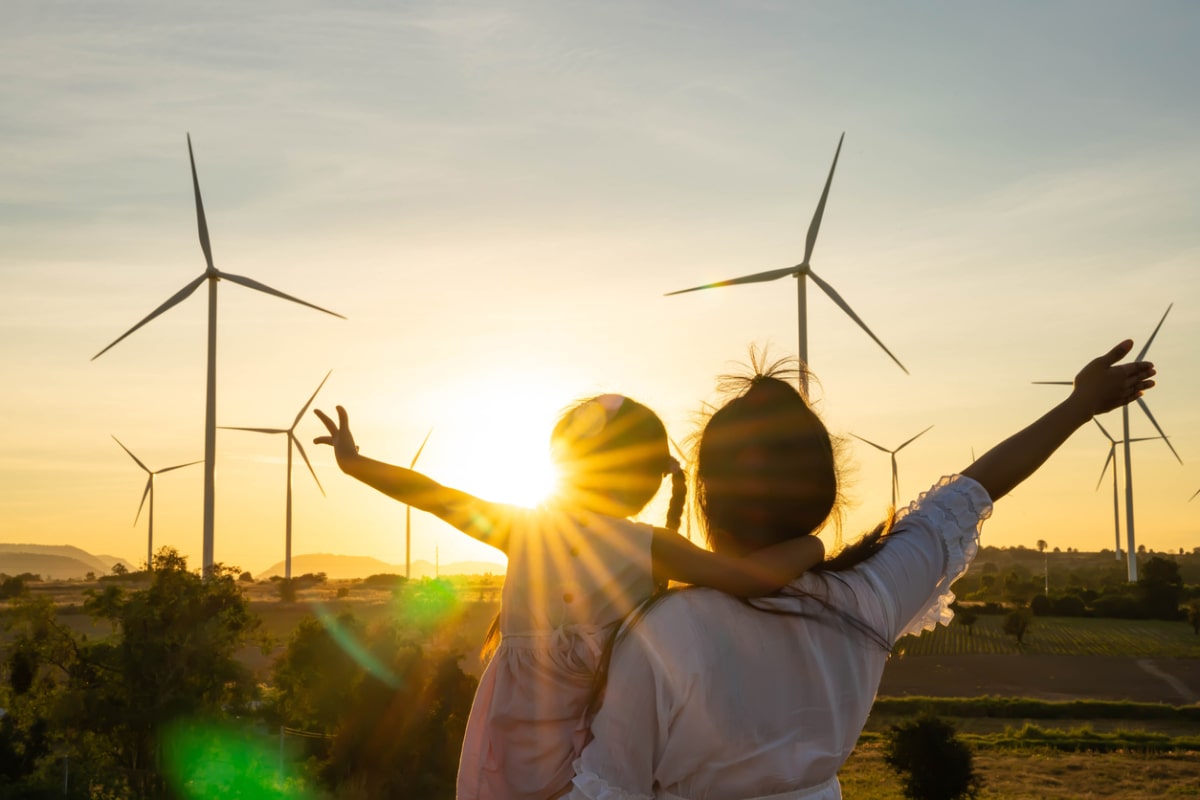 Deux personnes levant les mains devant des éoliens.